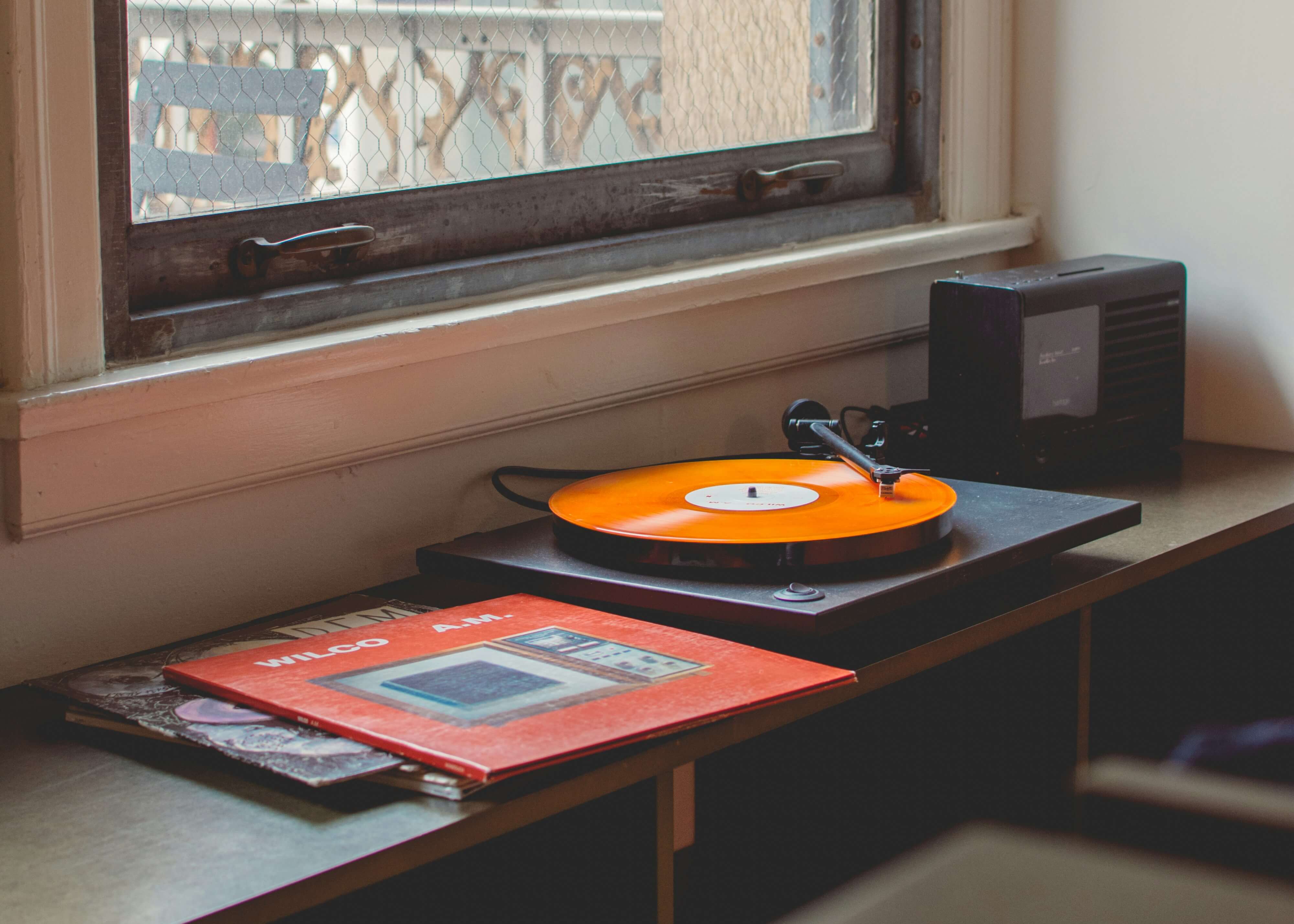 a photo of a record player in a window sile with an orange record on it
