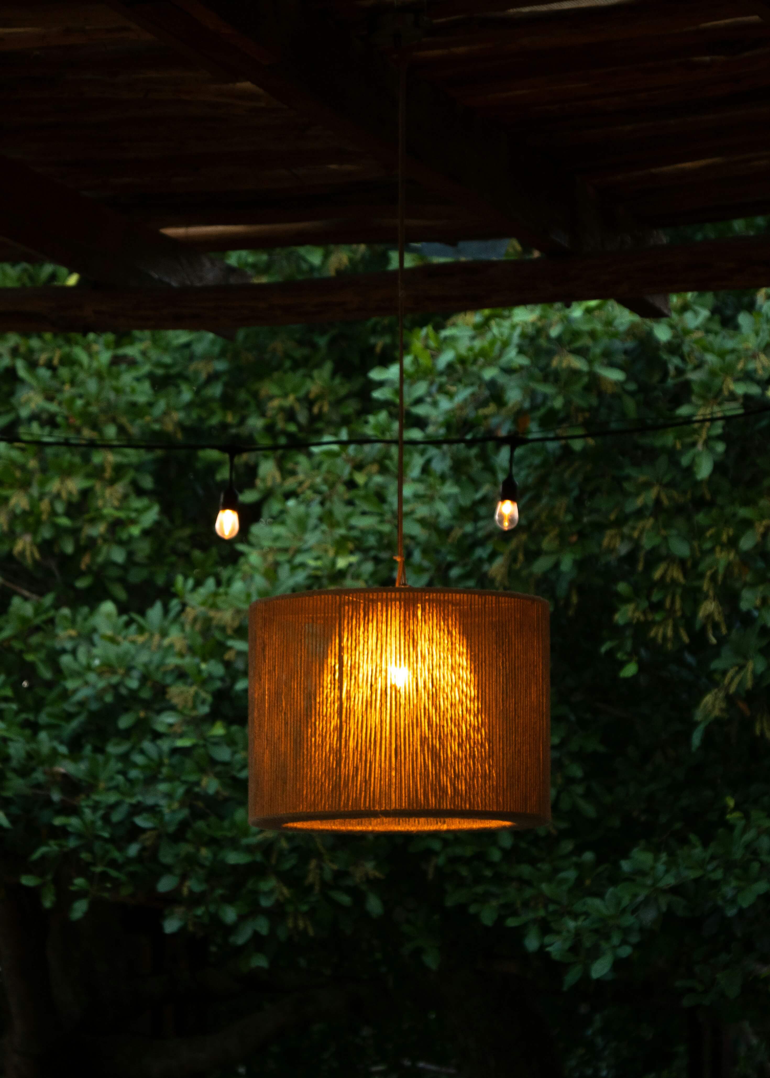 a photo of a warm lamp hanging outside in a darkly lit outdoor background