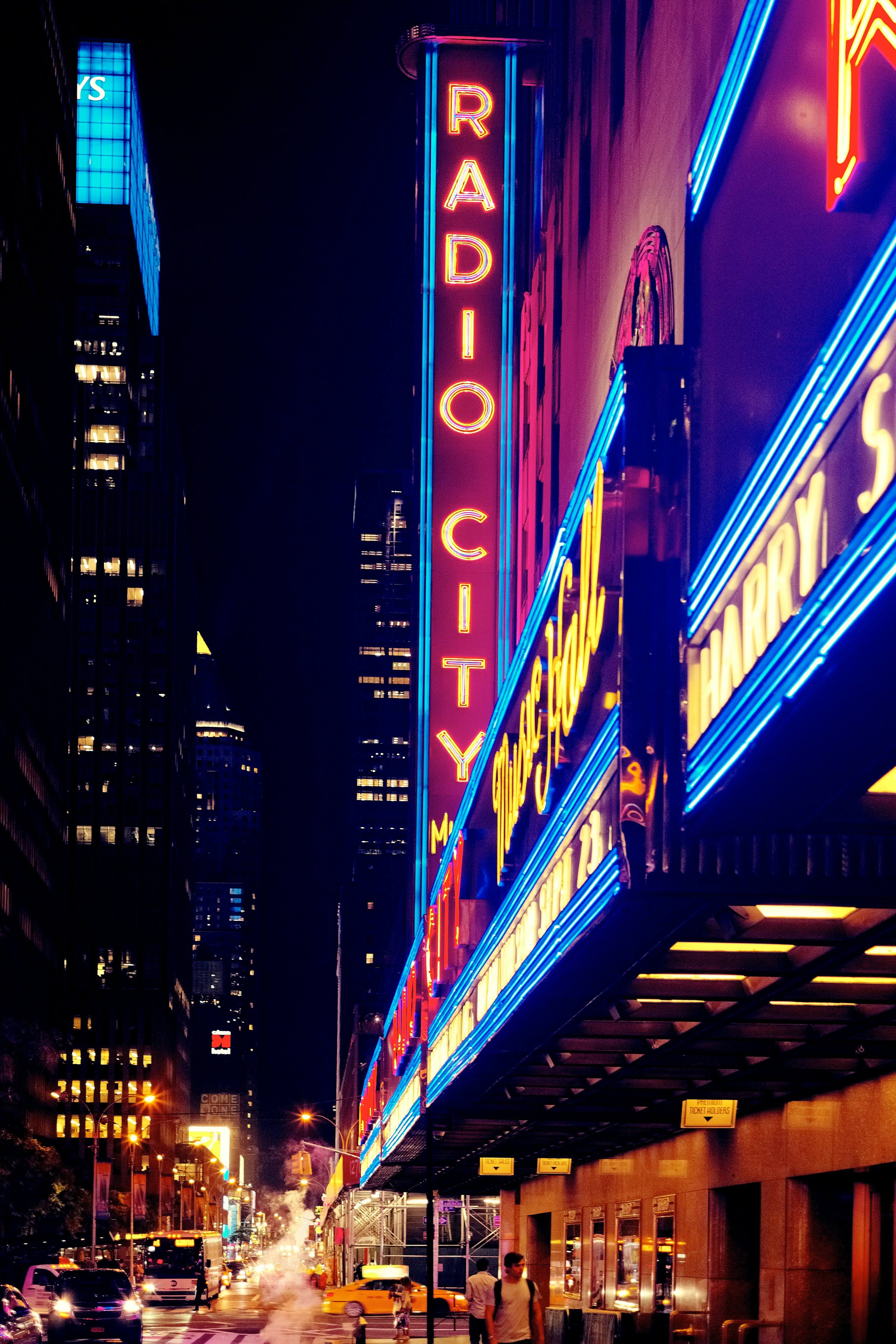 a photo of a neon theater sign in a city at night. The sign says Radio City