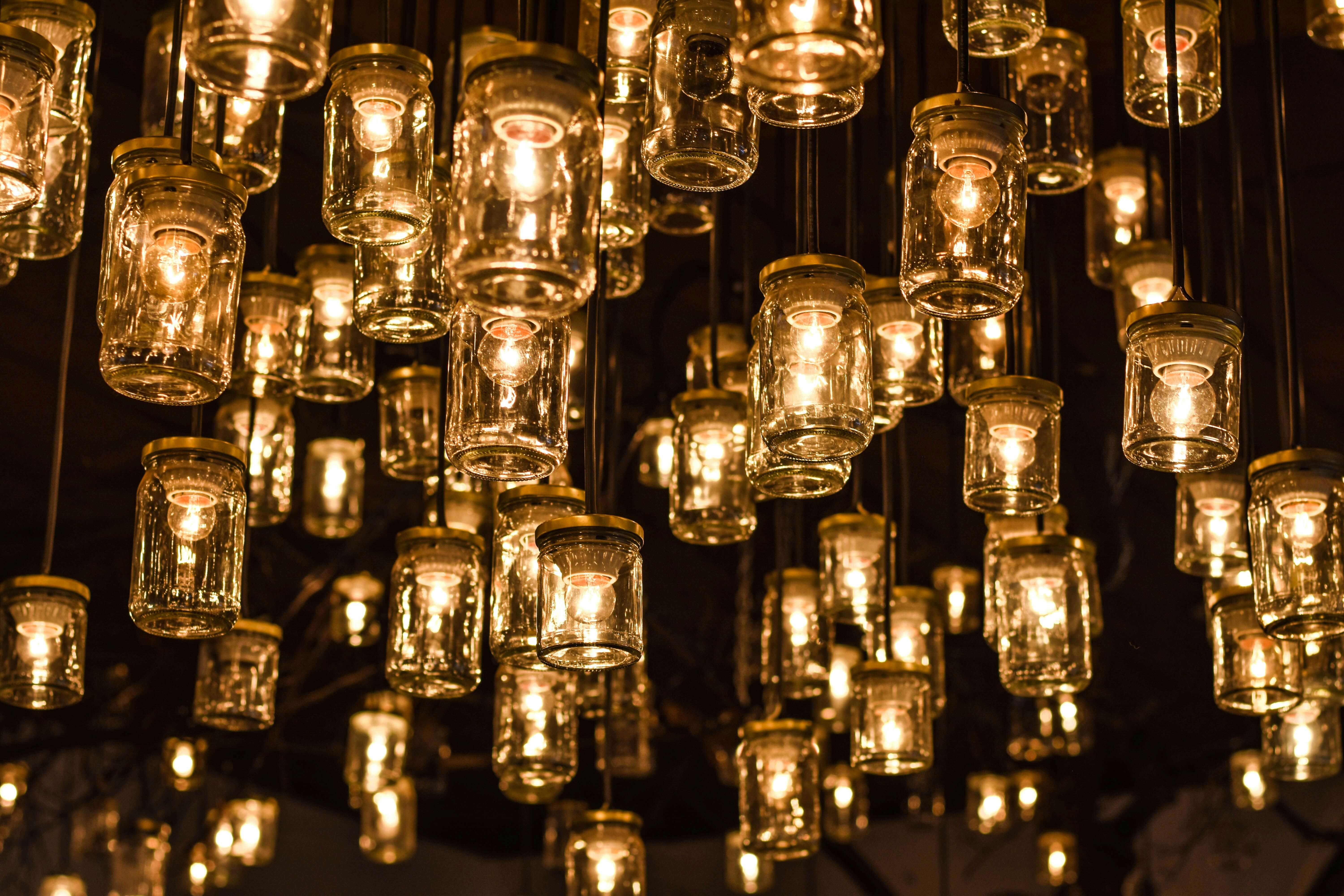 a photo of jars with warm fairy lights strung inside them and hung on the ceiling