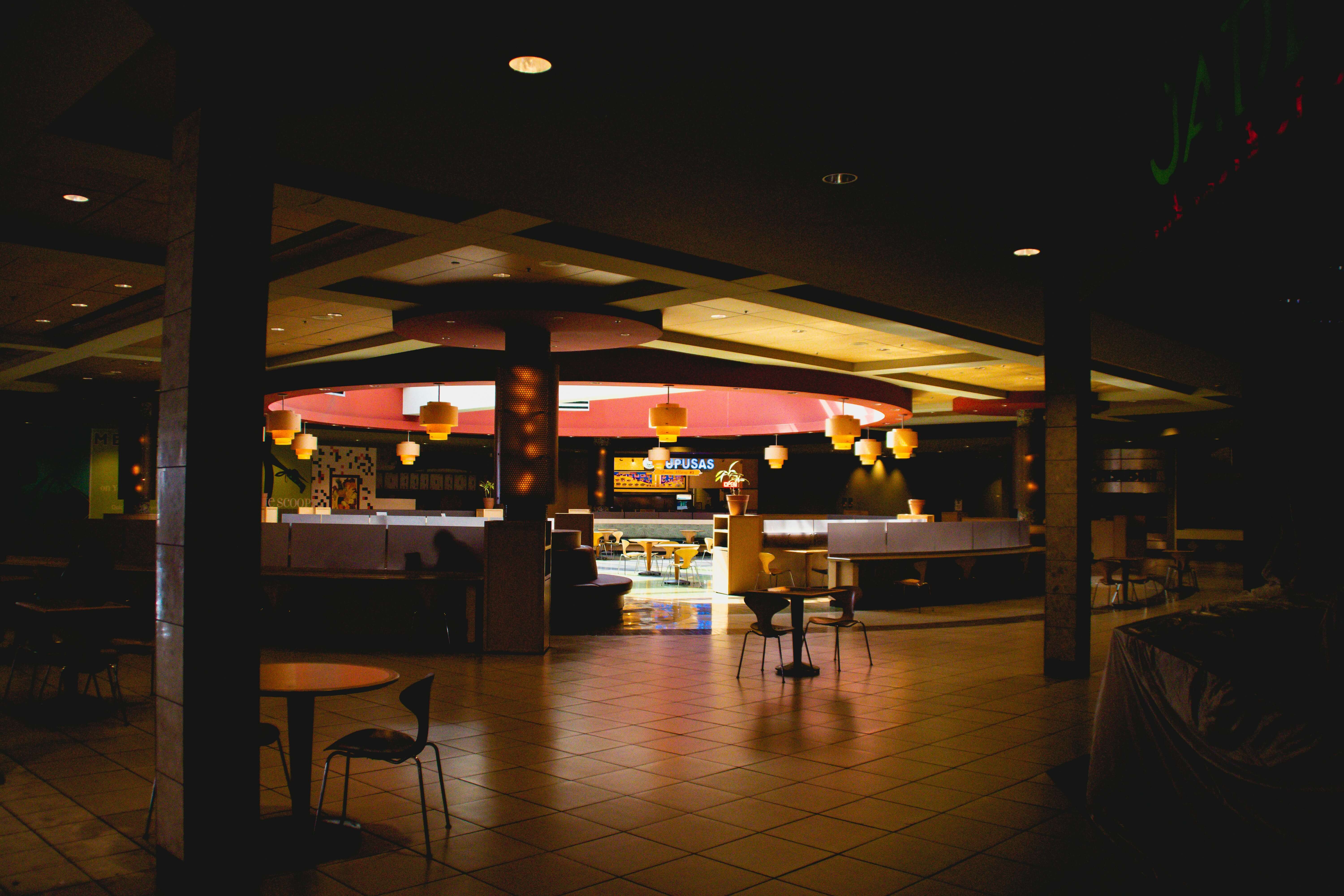 a photo of a dimmly illuminated empty indoor mall food court
