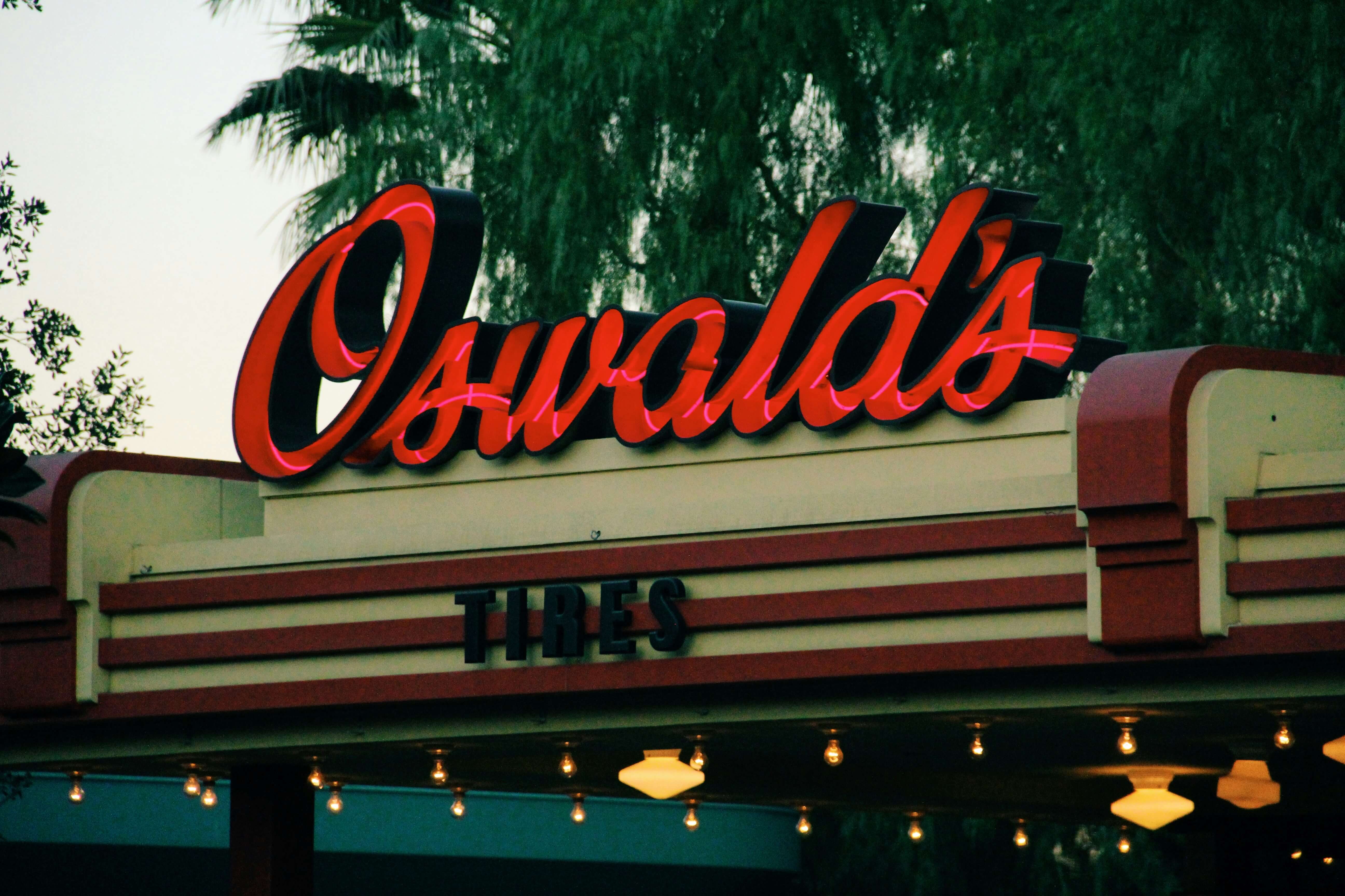 a photo of the front of a diner named Oswalds. There are tree's behind the sign