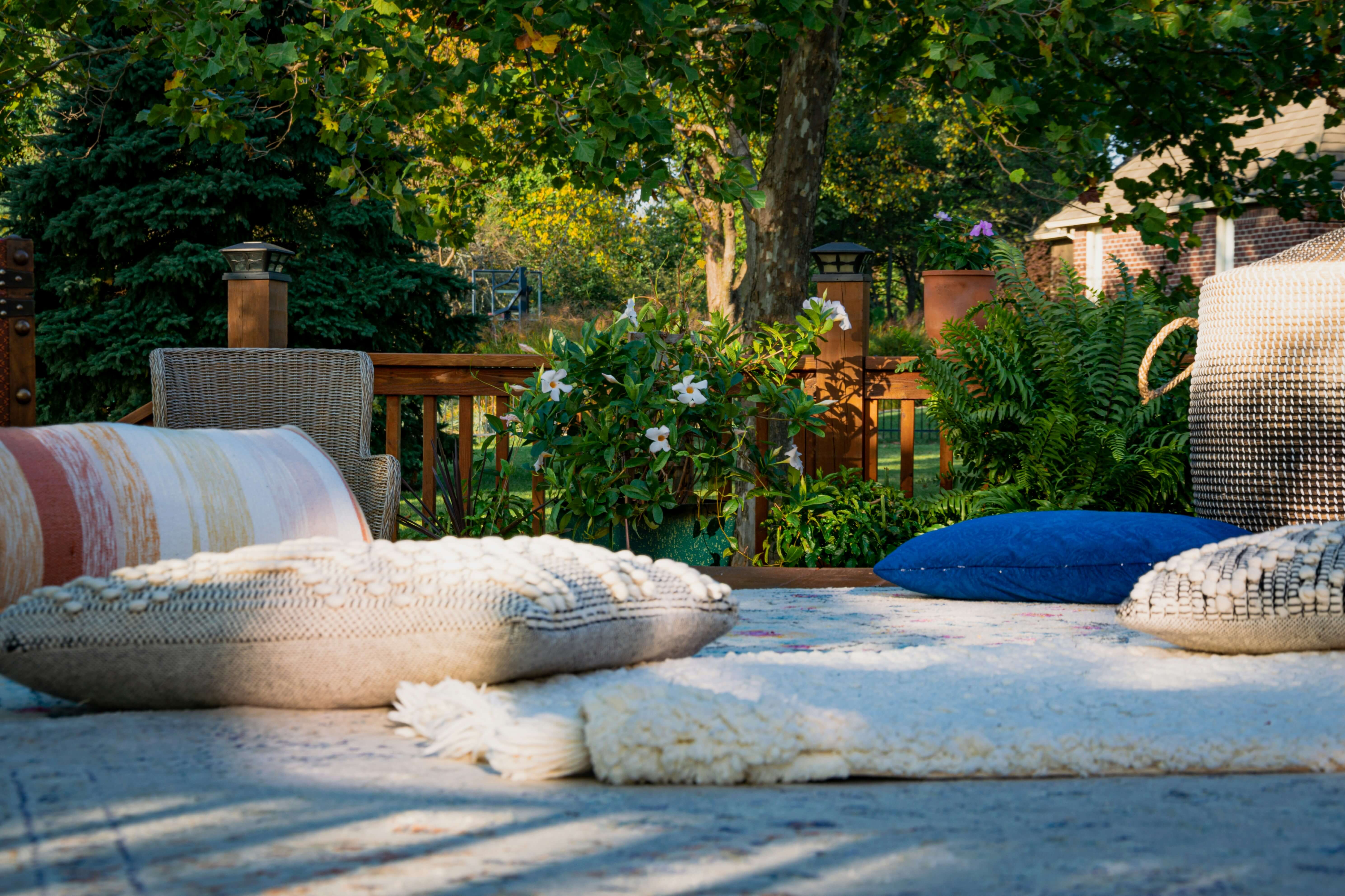 a photo of a white blanket with pillows surrounded by various different green folliage
