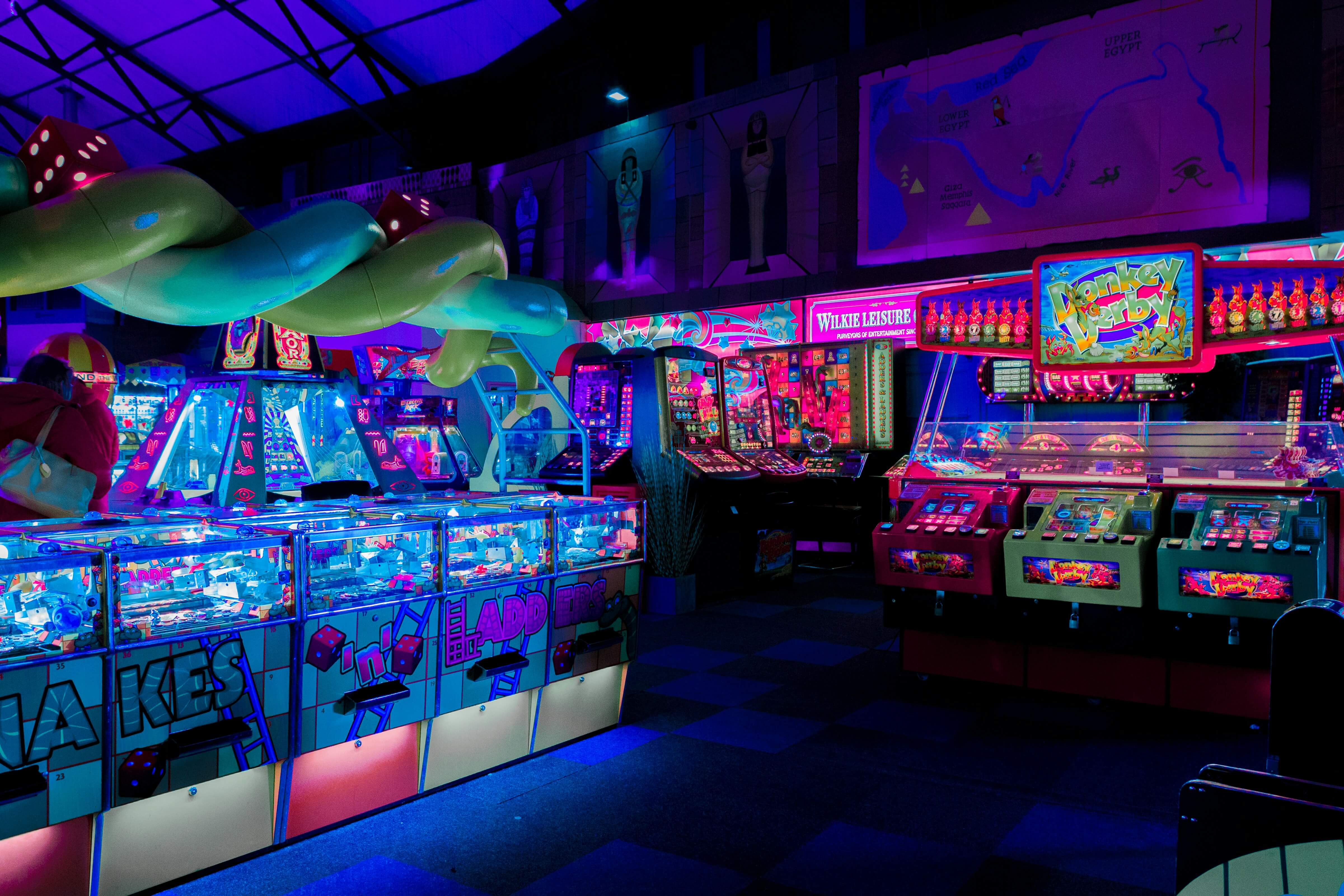 a photo of a neon lit arcade with various different arcade machines