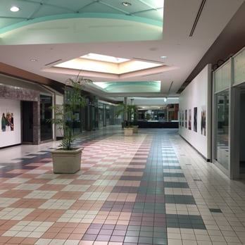 A picture of a dead mall hallway with 90’s style design and a pink, white, blue color scheme